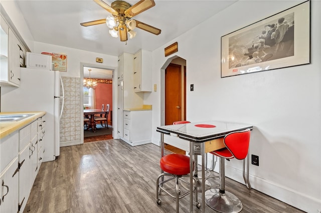 dining area with ceiling fan with notable chandelier and hardwood / wood-style floors