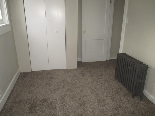 unfurnished bedroom featuring carpet flooring and radiator heating unit