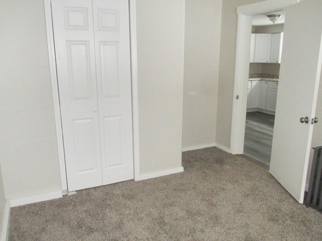 unfurnished bedroom with a closet, light carpet, and baseboards