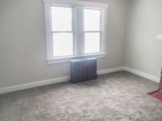 spare room featuring baseboards, carpet floors, and radiator