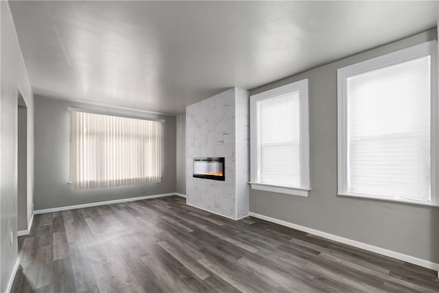 unfurnished living room with a tiled fireplace, plenty of natural light, and dark hardwood / wood-style flooring