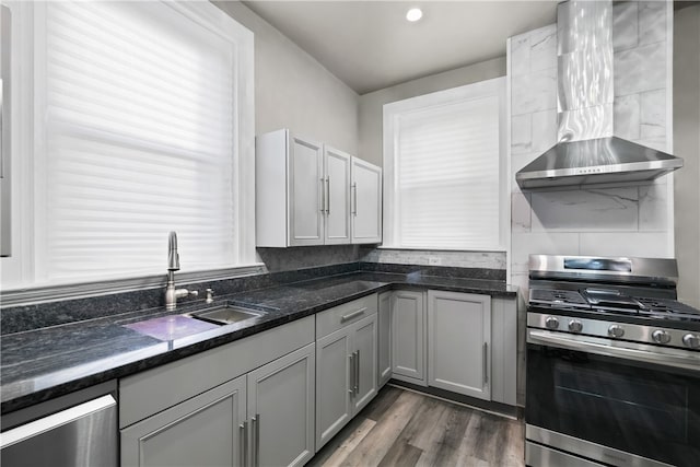 kitchen featuring sink, wall chimney range hood, stainless steel gas range, and a wealth of natural light