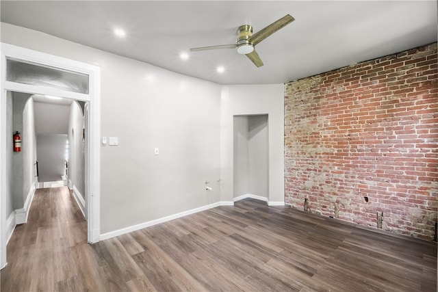 spare room featuring ceiling fan, dark hardwood / wood-style floors, and brick wall