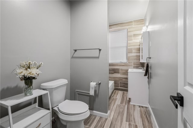 bathroom with tile walls, hardwood / wood-style flooring, and toilet