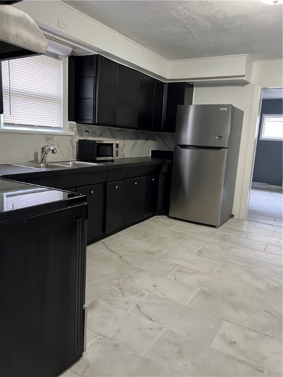 kitchen with stainless steel appliances, a textured ceiling, tasteful backsplash, and sink