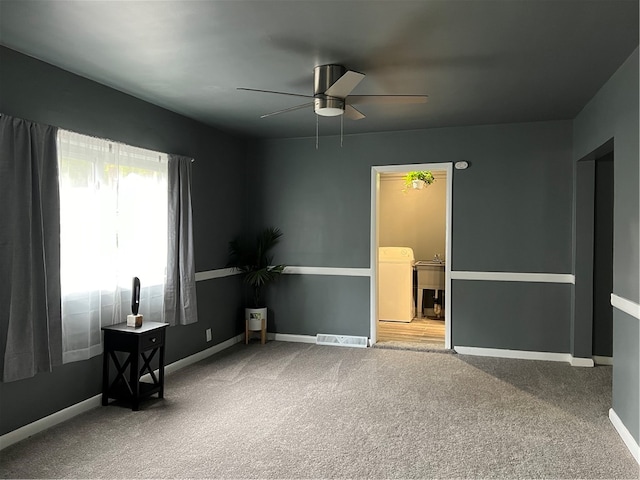 empty room featuring ceiling fan, carpet floors, and washer / dryer