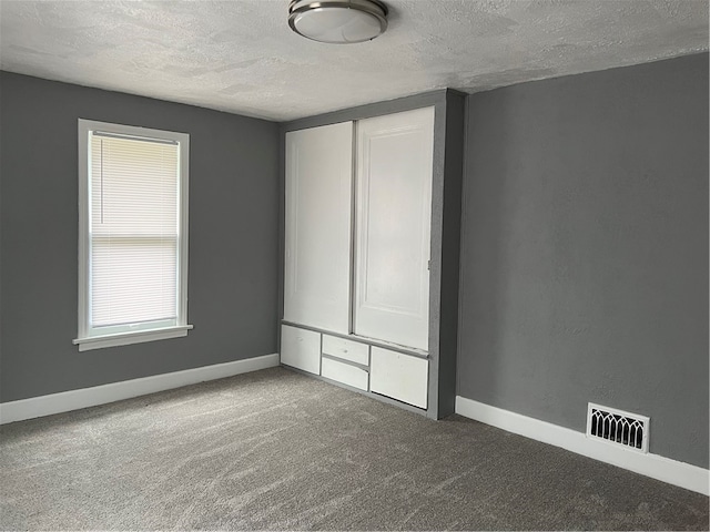 carpeted empty room featuring a textured ceiling