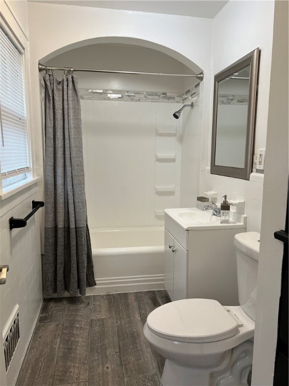 full bathroom featuring tile walls, hardwood / wood-style flooring, shower / tub combo, and toilet