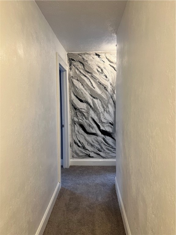 hallway featuring a textured ceiling and dark carpet