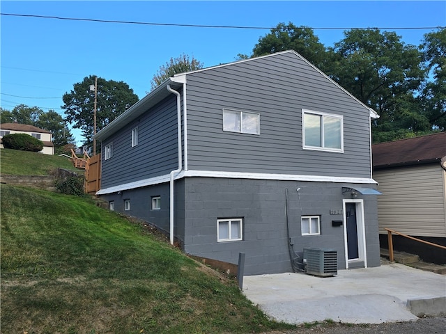 back of property with a lawn, cooling unit, and a patio area