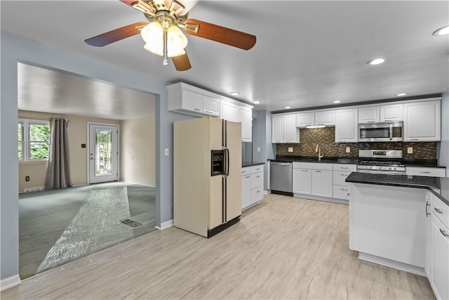 kitchen with appliances with stainless steel finishes, white cabinetry, backsplash, ceiling fan, and light hardwood / wood-style flooring