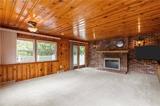 unfurnished living room featuring carpet, a wealth of natural light, ceiling fan, and a brick fireplace