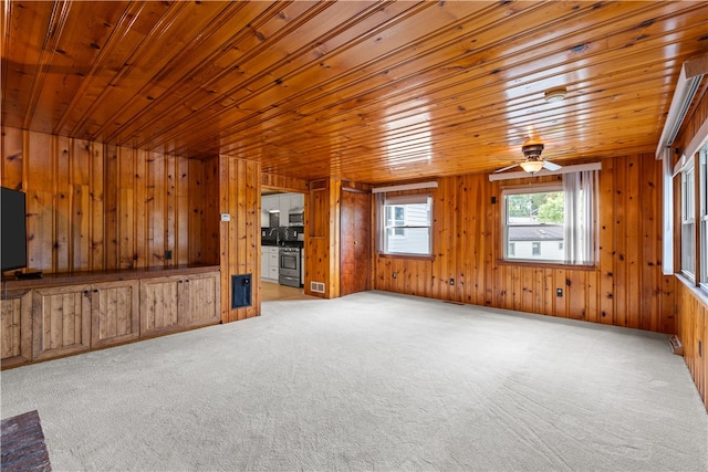 unfurnished living room with ceiling fan, light colored carpet, wooden walls, and wood ceiling