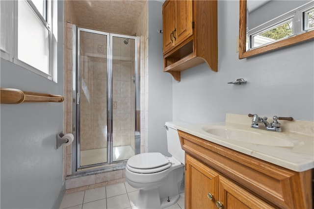 bathroom with a shower with door, toilet, vanity, and tile patterned floors