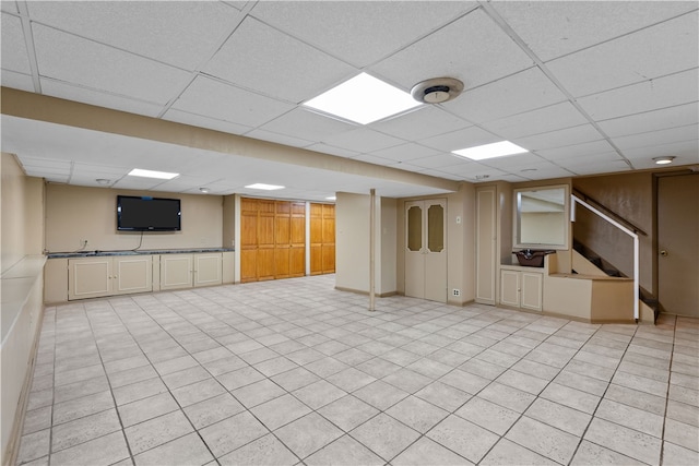 basement with a drop ceiling and light tile patterned floors