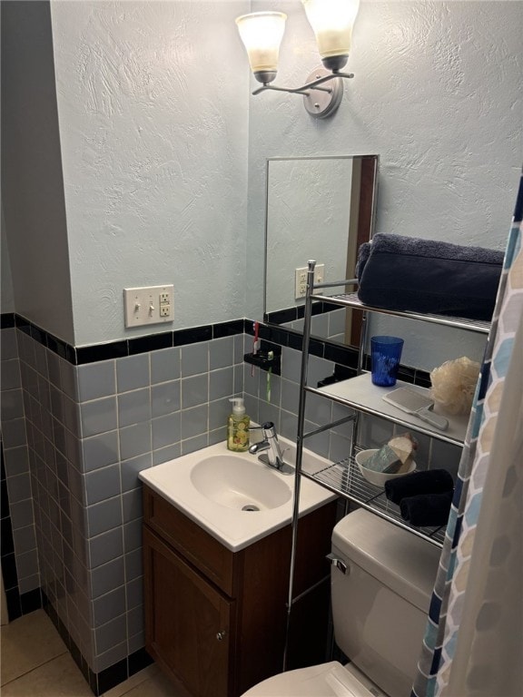 bathroom featuring tile patterned flooring, vanity, toilet, and tile walls