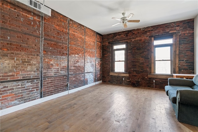 interior space with ceiling fan, brick wall, and plenty of natural light