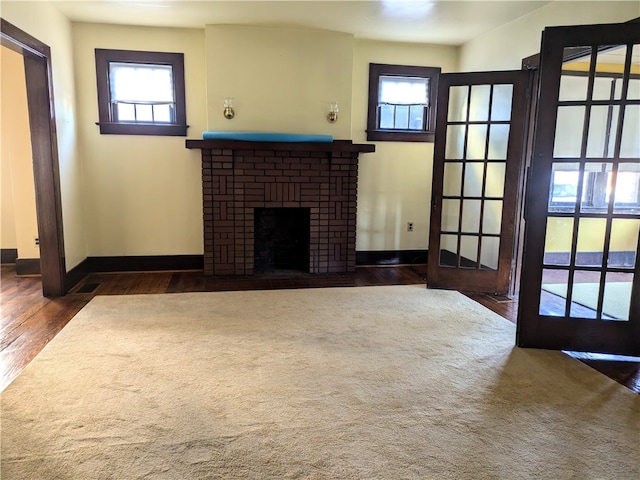 unfurnished living room featuring a brick fireplace and dark wood-type flooring