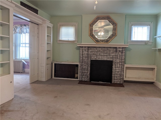 unfurnished living room featuring a healthy amount of sunlight, radiator, and a fireplace