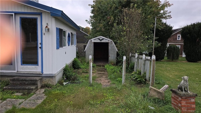 exterior space with a storage shed, a lawn, fence, and an outdoor structure