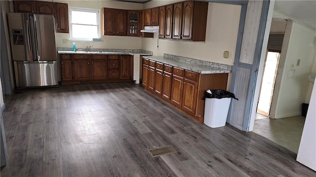 kitchen featuring dark wood finished floors, visible vents, under cabinet range hood, and stainless steel fridge with ice dispenser