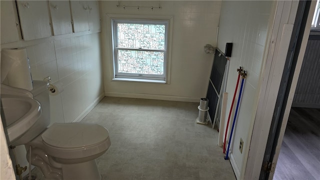 bathroom with toilet and tile walls