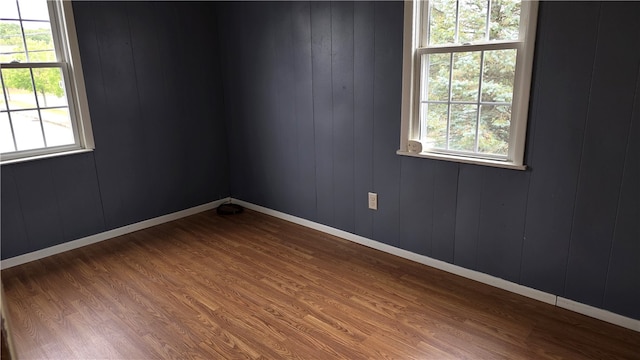 spare room with hardwood / wood-style floors, plenty of natural light, and wood walls