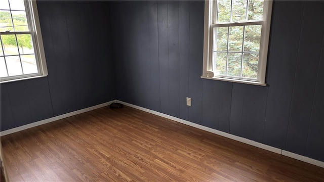 spare room with wood finished floors, a healthy amount of sunlight, and baseboards