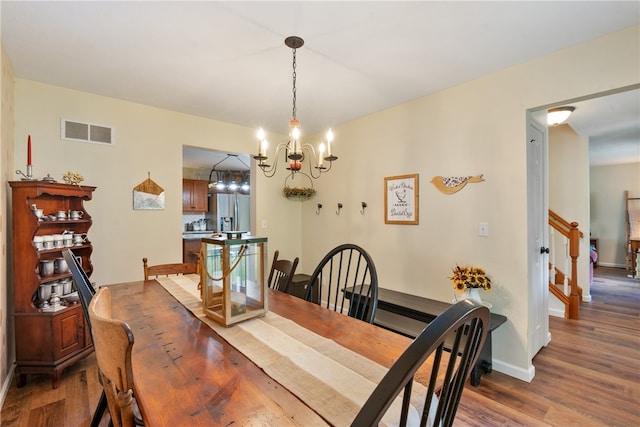 dining area with hardwood / wood-style floors and an inviting chandelier