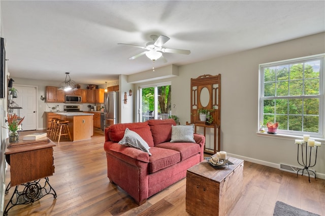 living room featuring light hardwood / wood-style floors, ceiling fan, and a healthy amount of sunlight