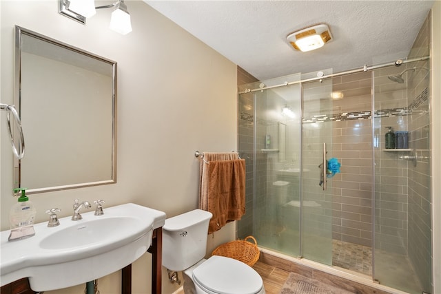 bathroom with toilet, an enclosed shower, hardwood / wood-style floors, and a textured ceiling