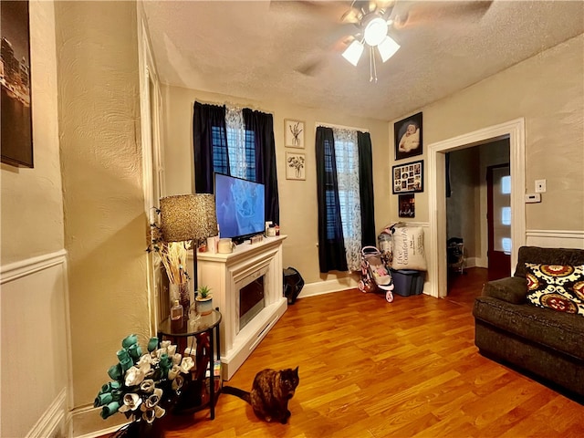 living room featuring a textured ceiling, light hardwood / wood-style flooring, and ceiling fan