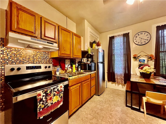 kitchen featuring sink, tasteful backsplash, plenty of natural light, and electric stove