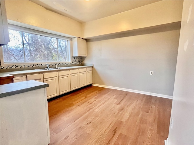 kitchen featuring light wood-type flooring, backsplash, and sink