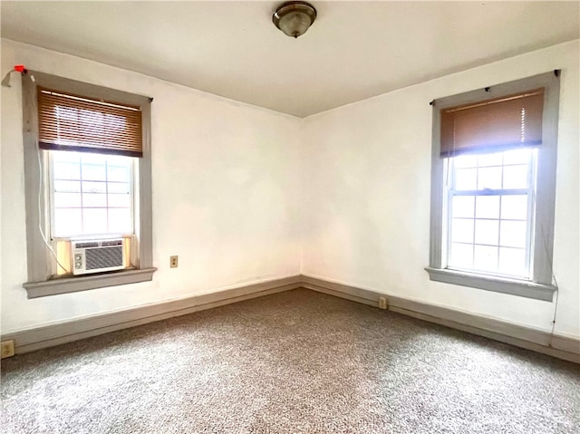 empty room featuring carpet flooring, a wealth of natural light, and cooling unit