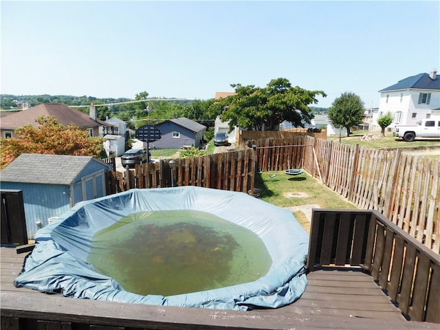 view of pool featuring a deck and a storage shed