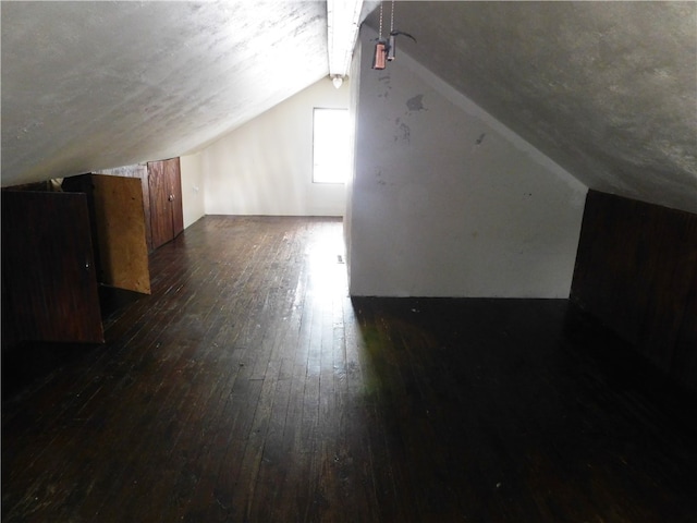 additional living space featuring lofted ceiling and dark hardwood / wood-style flooring