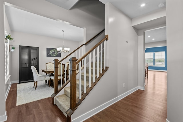 stairs featuring a chandelier and hardwood / wood-style floors