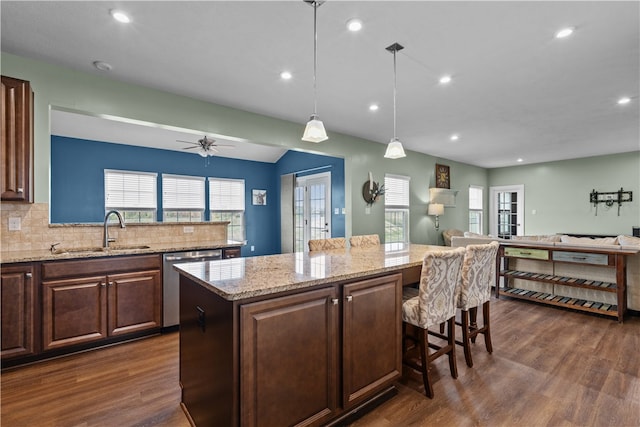 kitchen featuring dishwasher, dark wood-type flooring, a center island, and decorative light fixtures