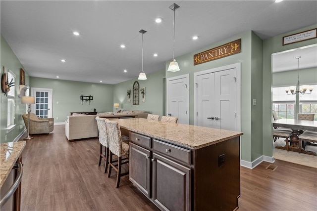 kitchen with a kitchen breakfast bar, hanging light fixtures, dark brown cabinetry, and dark hardwood / wood-style flooring