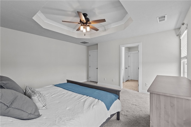 carpeted bedroom featuring a raised ceiling and ceiling fan