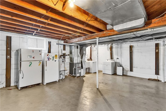 basement with heating unit, water heater, washing machine and clothes dryer, and white fridge