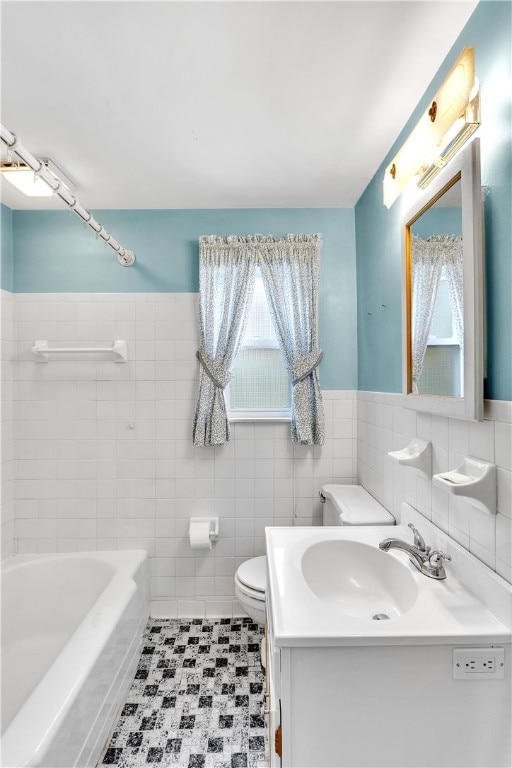 bathroom with vanity, tile walls, toilet, and a washtub