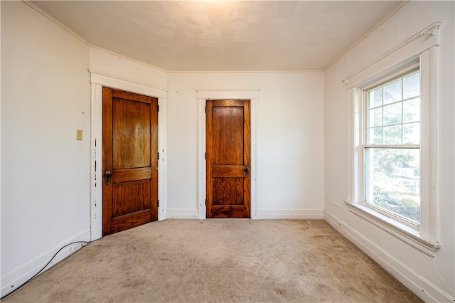 unfurnished bedroom with light carpet, multiple windows, and crown molding