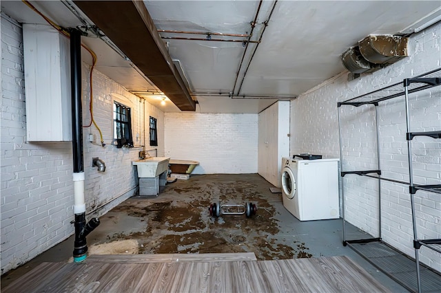 basement with brick wall and washer / clothes dryer