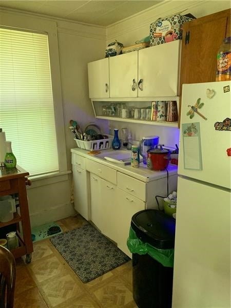 kitchen featuring white refrigerator, sink, ornamental molding, and light parquet flooring