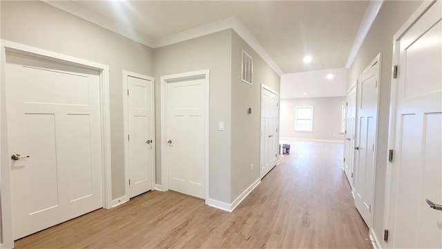 hall featuring crown molding, baseboards, visible vents, and light wood finished floors