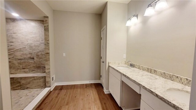 bathroom with hardwood / wood-style floors, vanity, and a shower