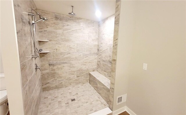 bathroom with a tile shower and toilet