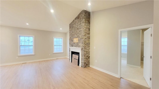 unfurnished living room featuring a fireplace, light hardwood / wood-style floors, and lofted ceiling